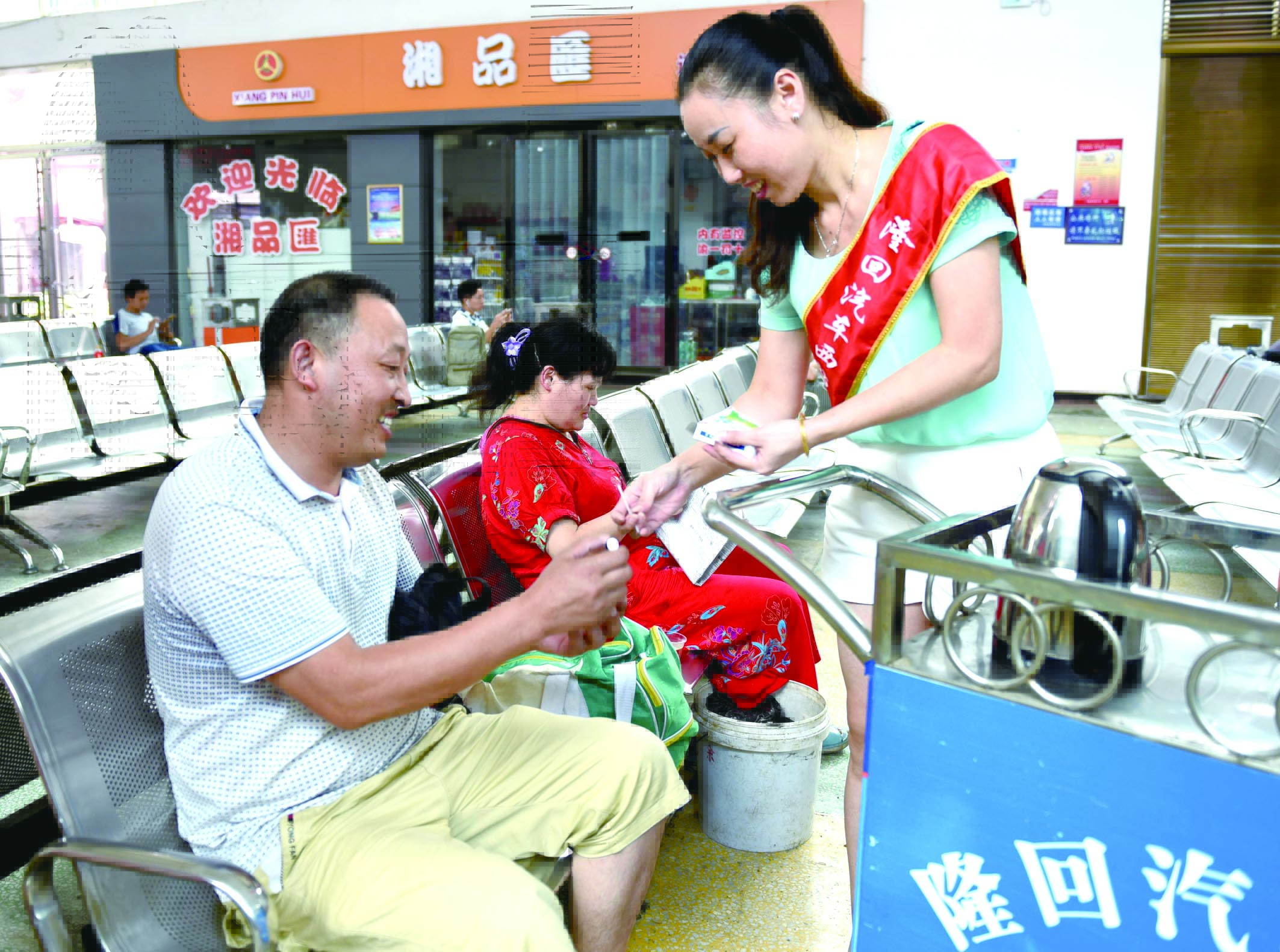 隆回分公司汽車西站工作人員正在為旅客免費贈送藿香正氣水。